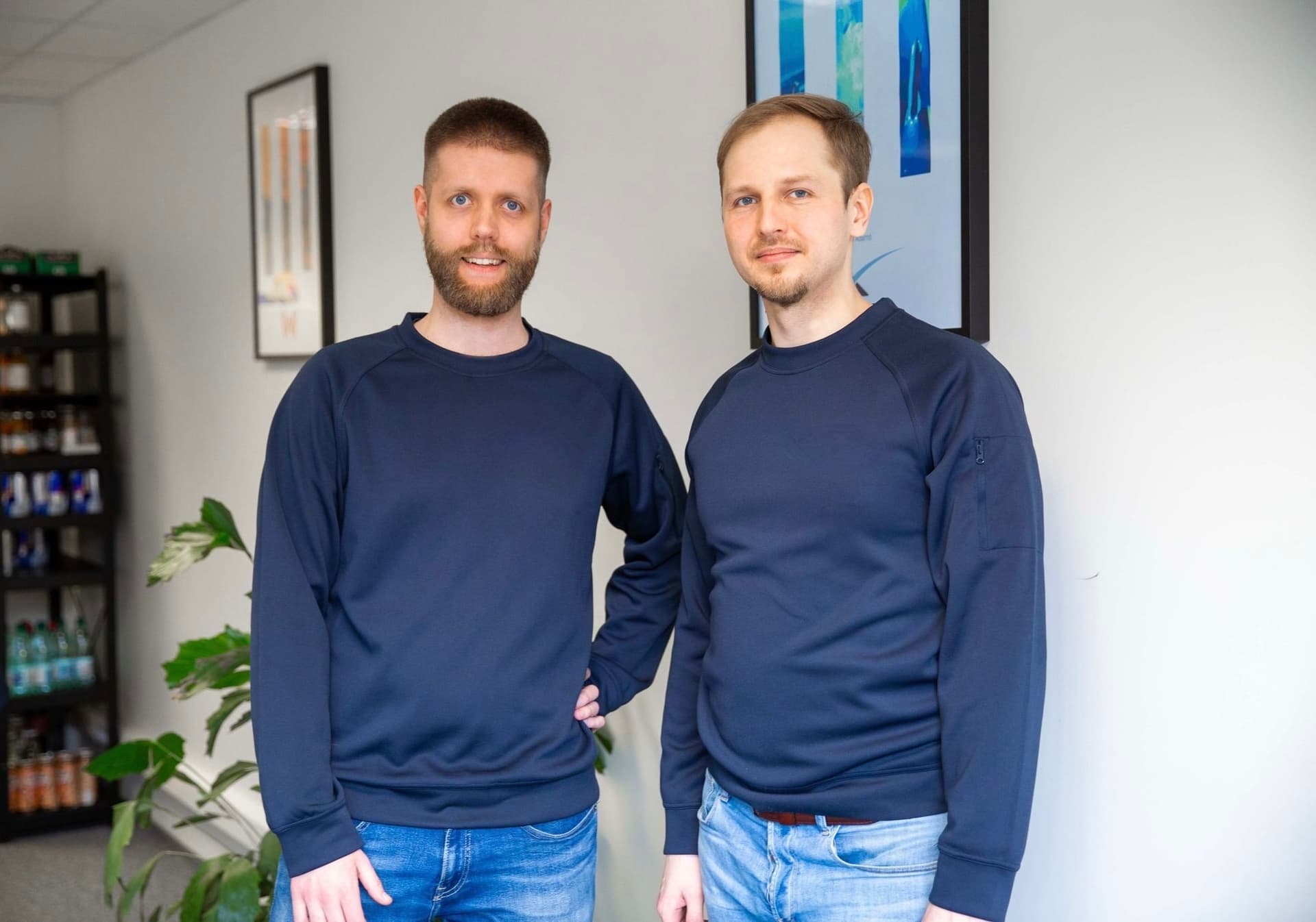 Two men in casual blue sweatshirts standing indoors
