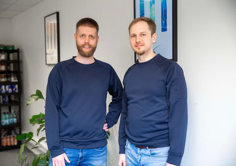 Two men in casual blue sweatshirts standing indoors