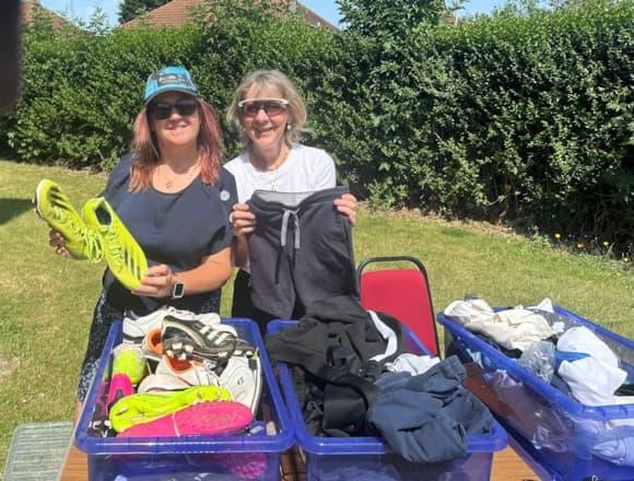 Two women smiling at outdoor charity sale with sportswear