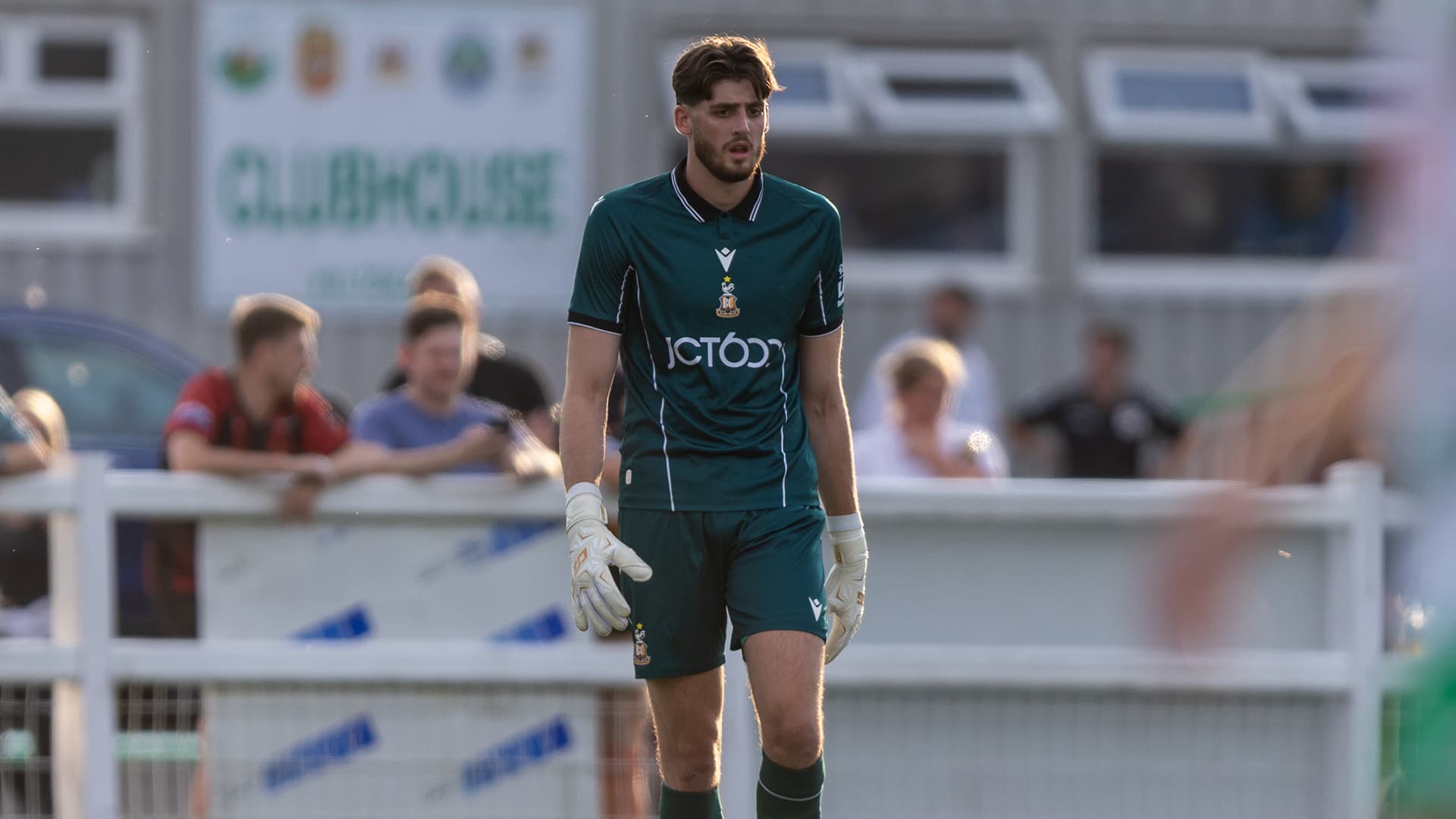 Football goalkeeper in green kit walking on pitch during a match