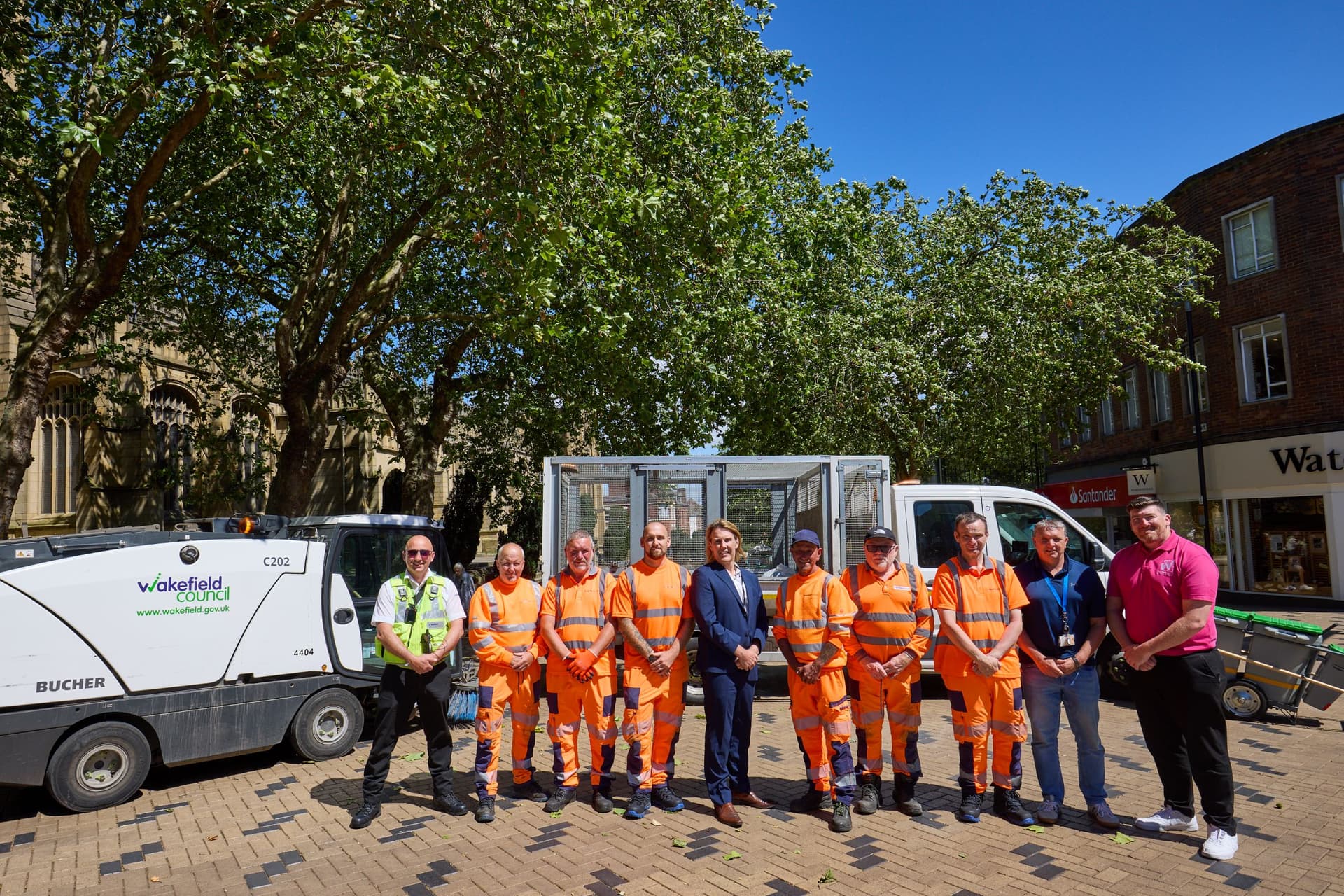 Group of workers in orange uniforms with street cleaning vehicles