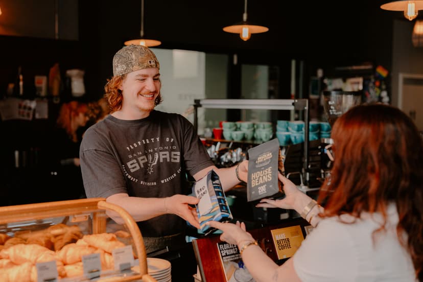 Barista handing coffee bag to customer in cozy cafe