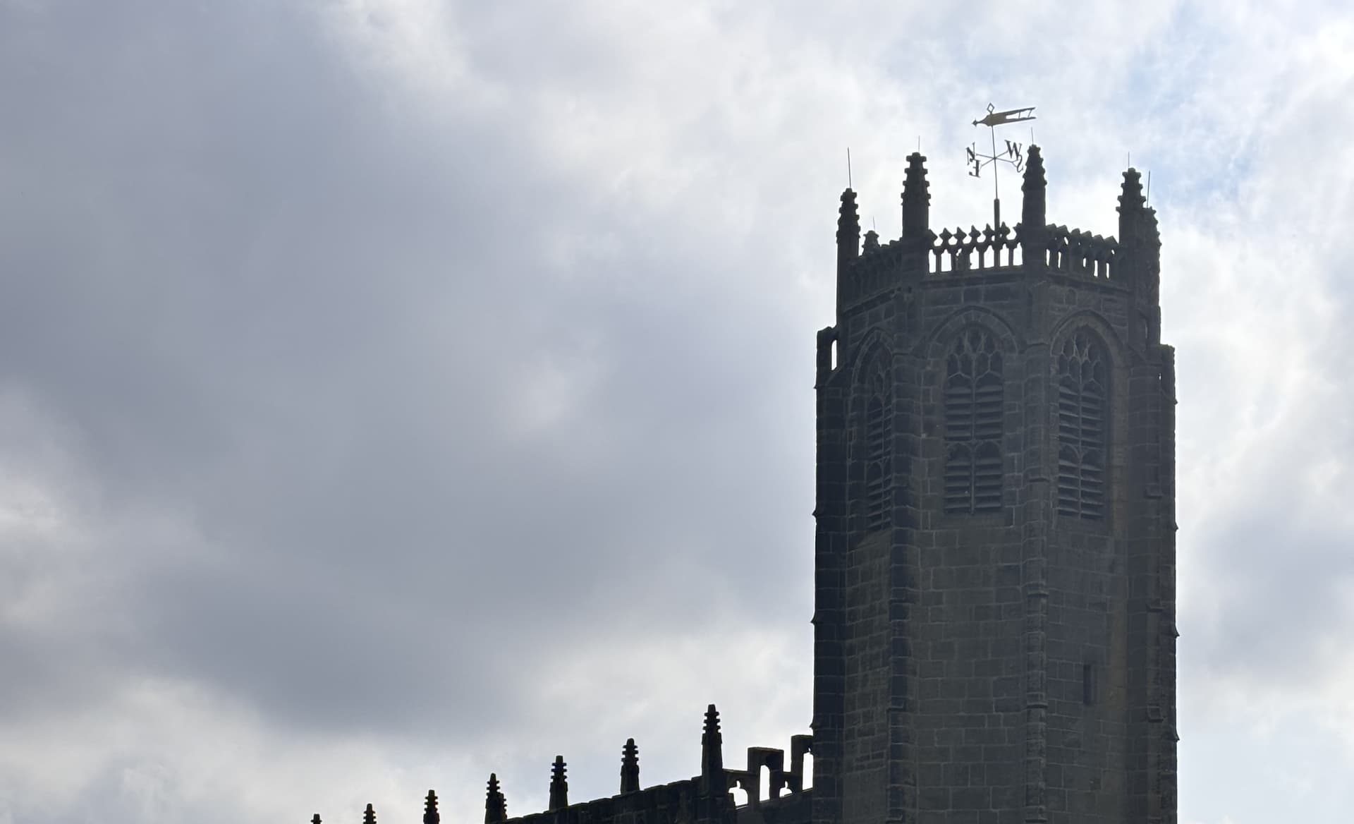 Gothic church tower with ornate spires against cloudy sky