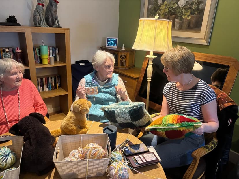 Three women knitting together in a cozy living room setting