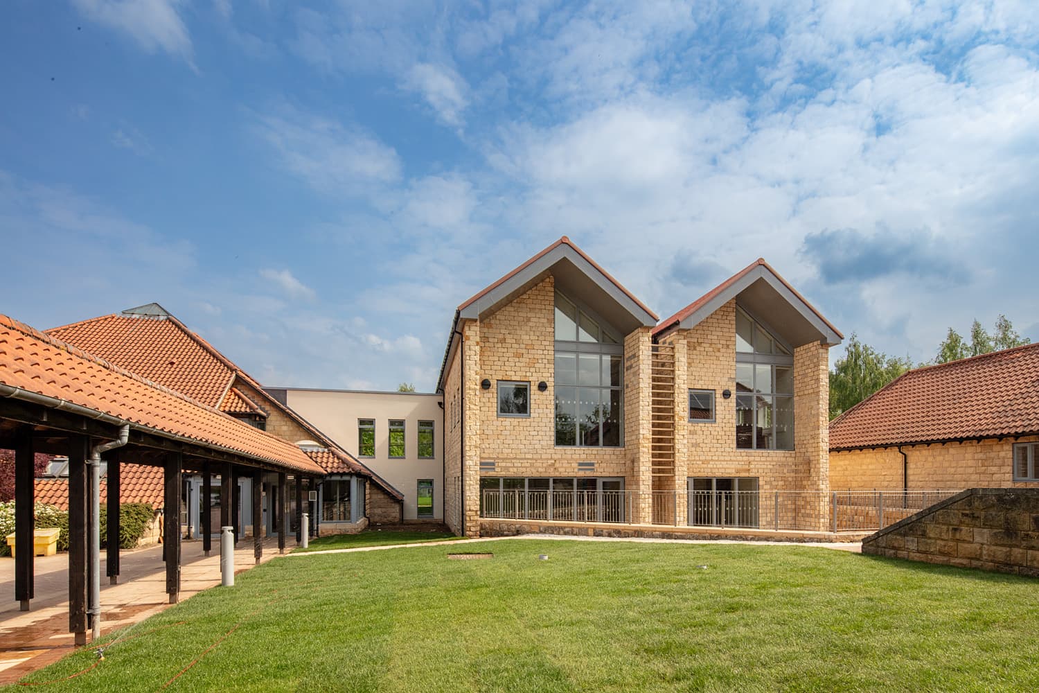 Modern stone building with red-tiled roofs and large glass windows