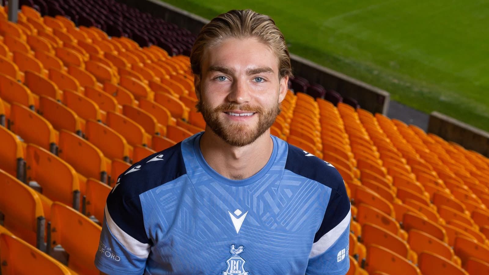 Smiling man in blue sports jersey in empty stadium seats