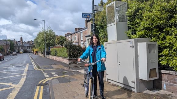 Person in blue jacket with bike on rainy Yorkshire street