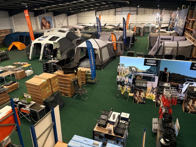 A spacious outdoor showroom filled with tents, camping gear, and promotional displays, showcasing a vibrant customer experience.
