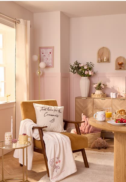 Cosy living room with pink walls, wooden furniture, and a yellow armchair