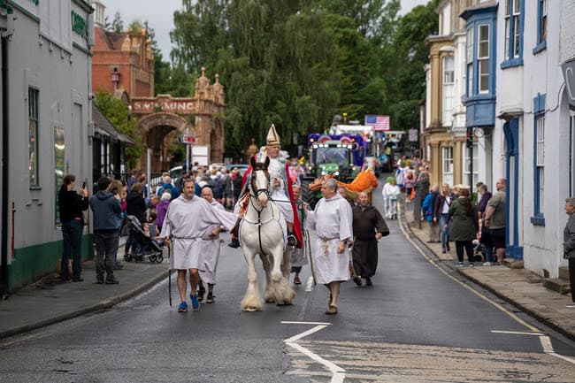 Historical parade with costumed figures and horse on village street