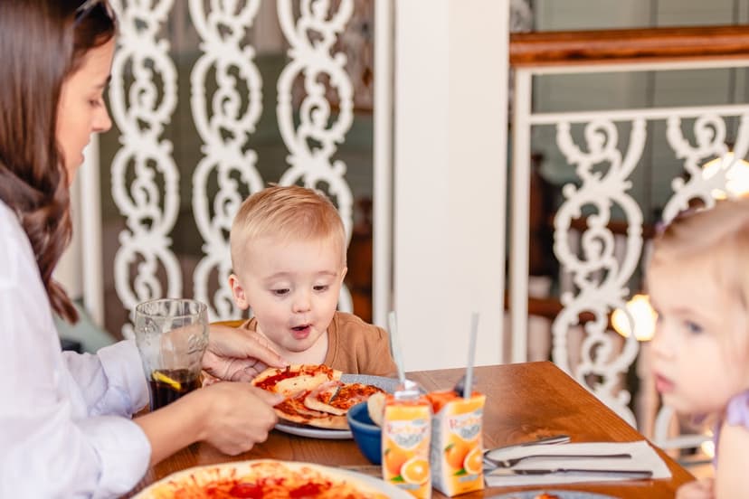 Family enjoying pizza at a cozy cafe with ornate railing