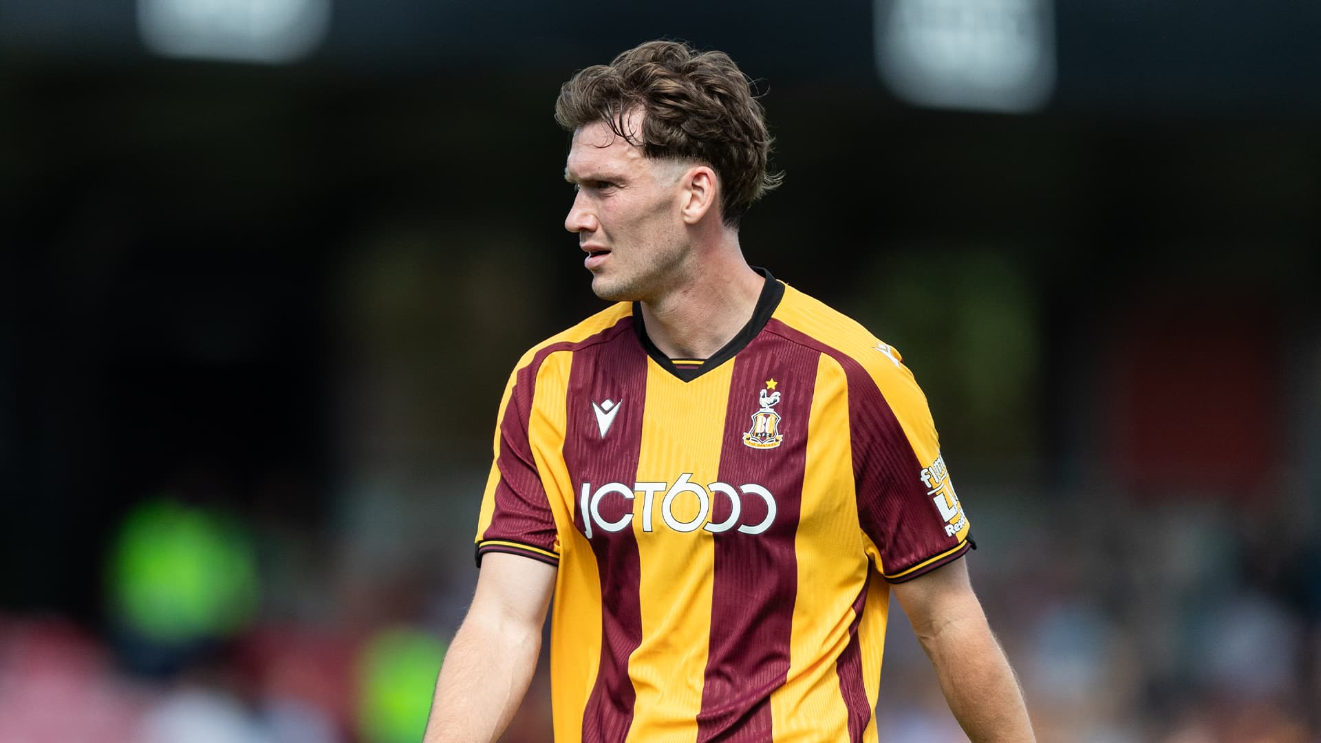 Footballer in claret and amber kit on pitch during match