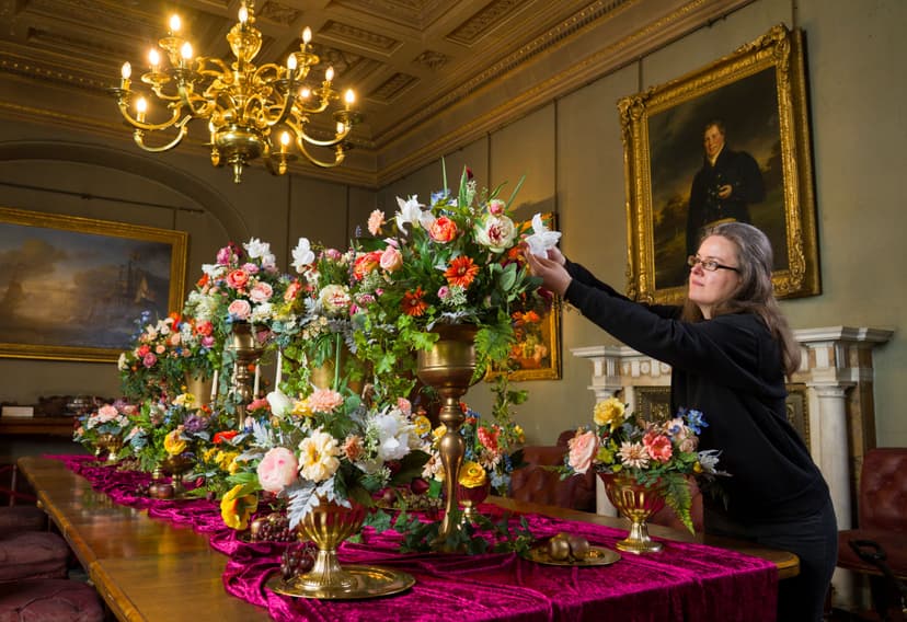Woman arranging colorful flowers on a grand dining table