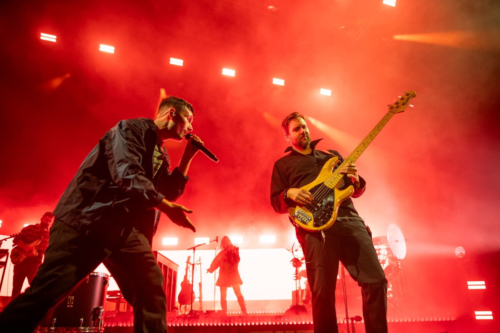 Energetic band performing on stage with vibrant red lighting