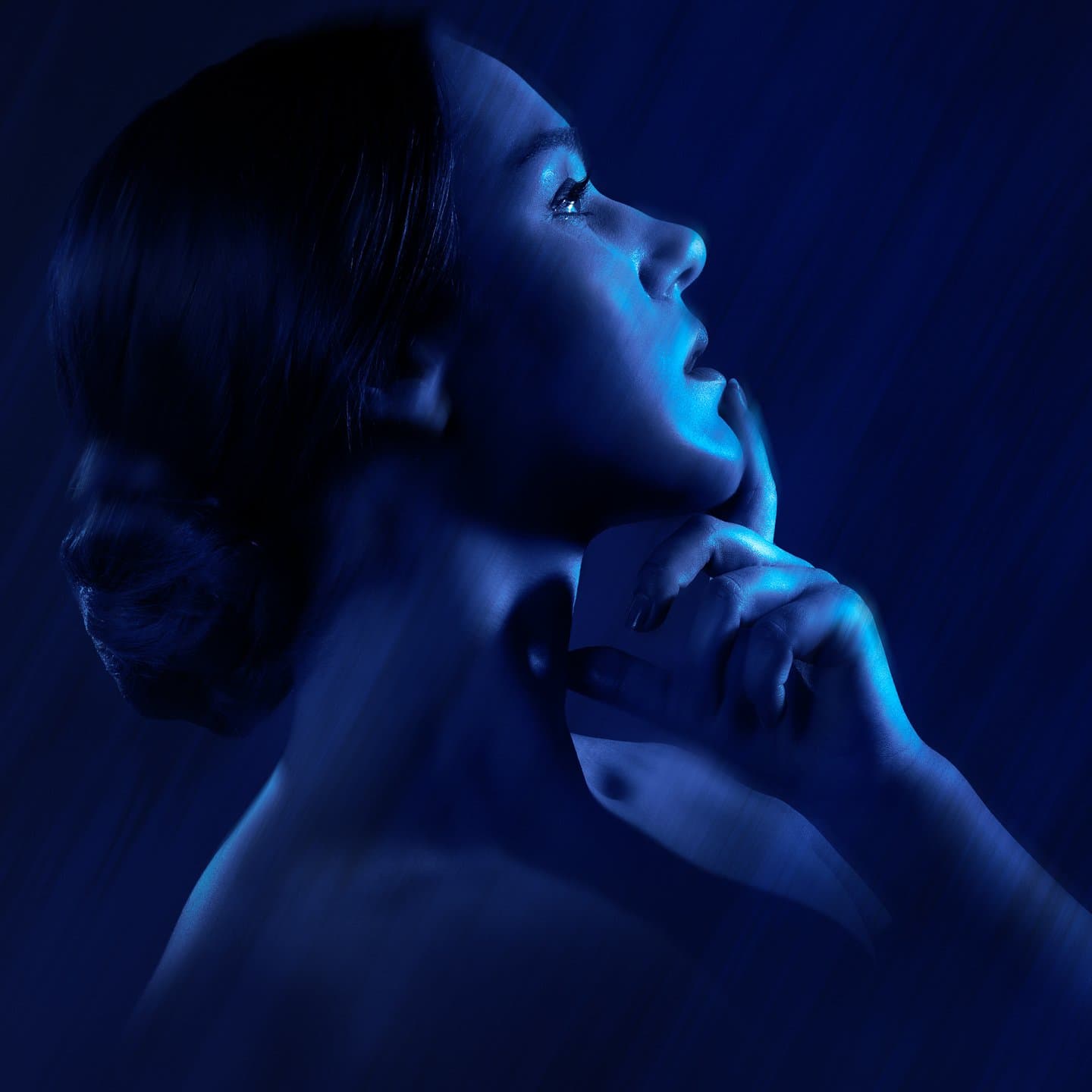 Silhouetted woman in blue light with contemplative pose
