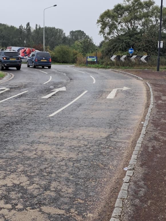 Roundabout with road signs and cars on a cloudy day