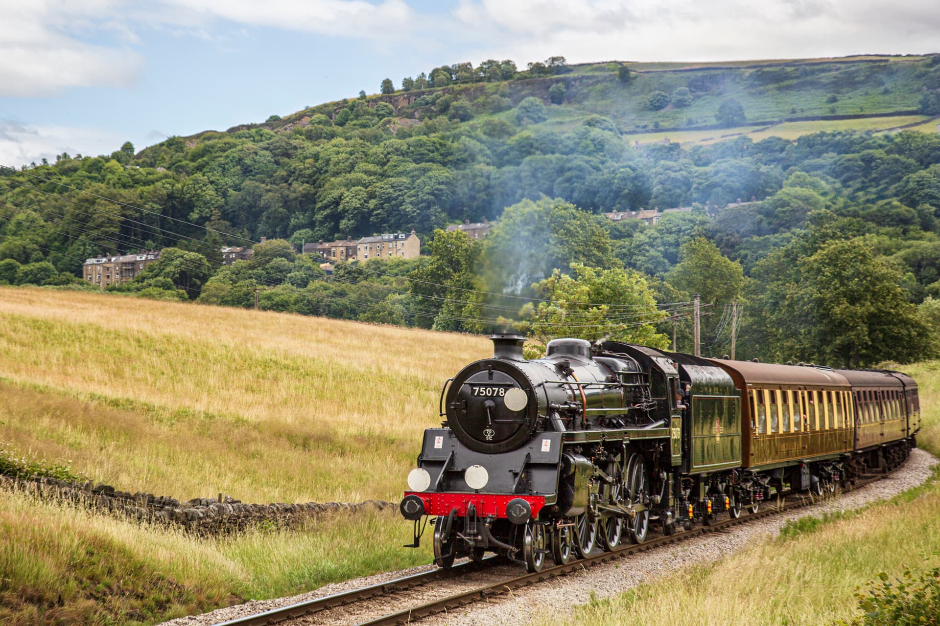 Historic steam train travelling through lush Yorkshire countryside