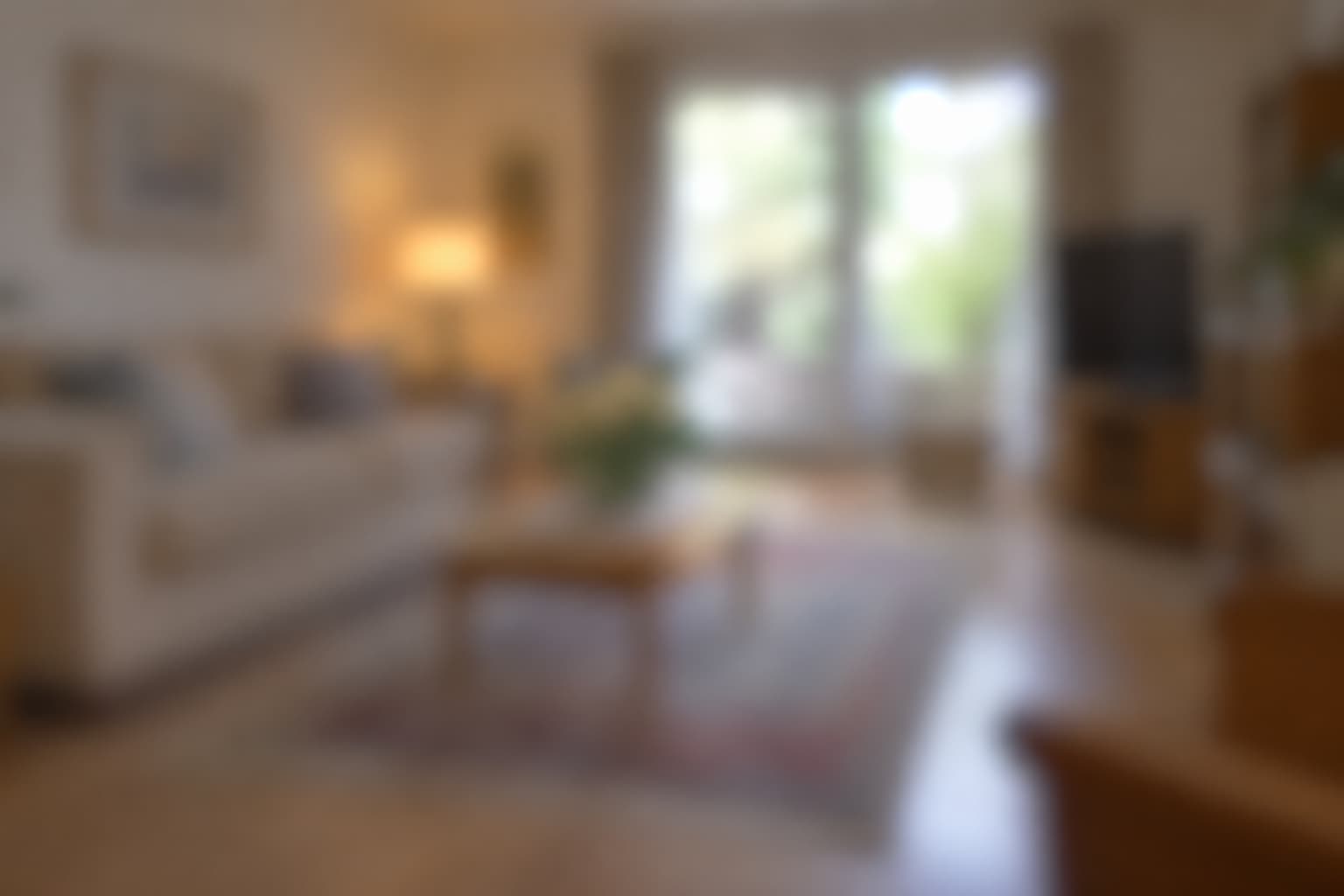 Cosy living room with beige sofa, wooden table, and large window