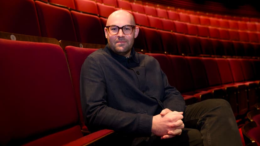 Person seated in an empty theater with red velvet seats