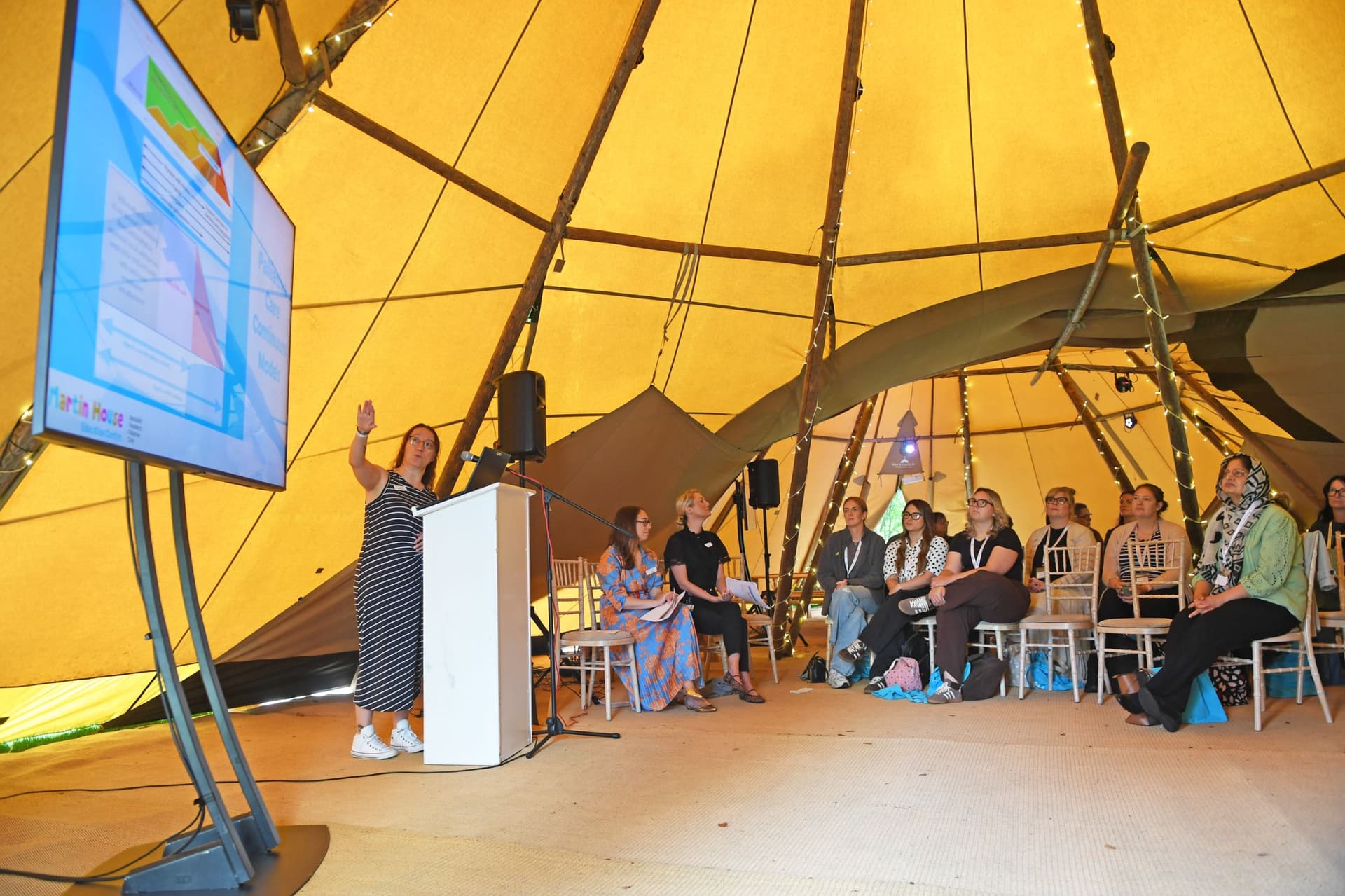 Group of people attending a presentation inside a tipi tent