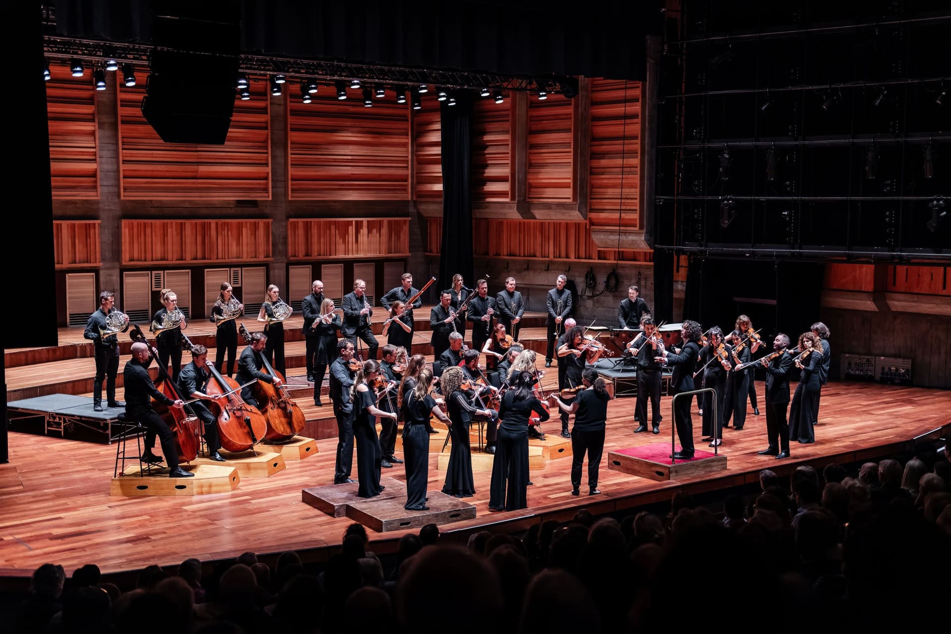 Orchestra performing on stage in a wooden concert hall