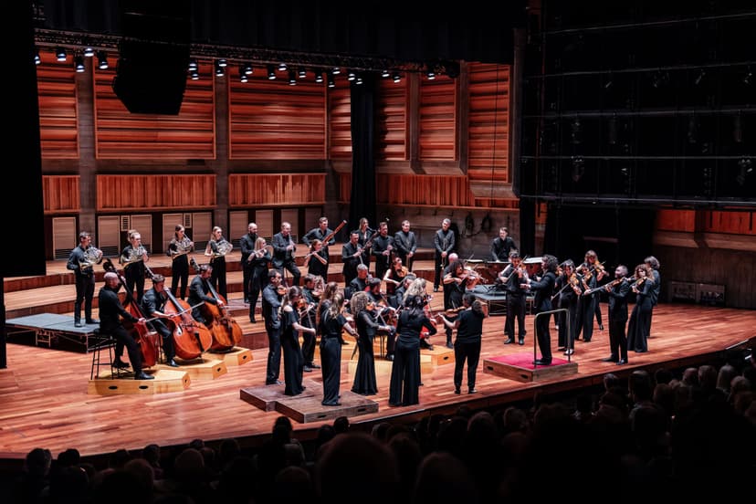 Orchestra performing on stage in a wooden concert hall
