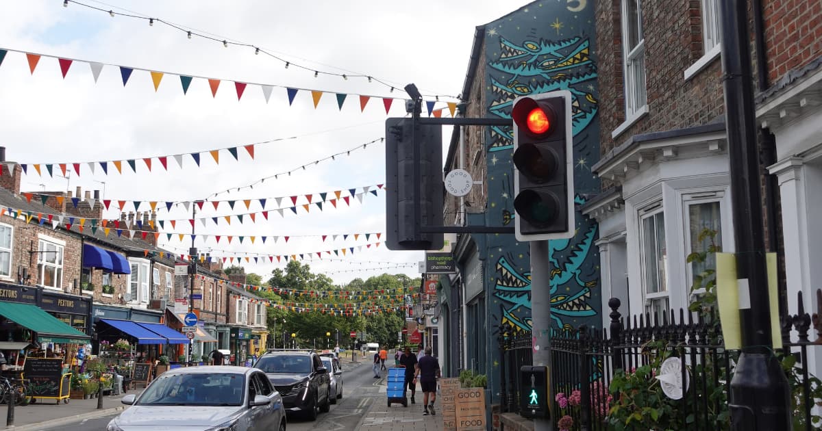 Bustling street in York with shops, bunting and traffic lights