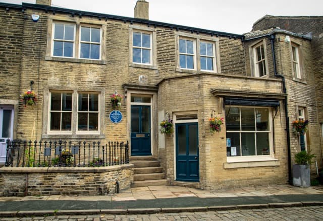 Historic stone terrace house with blue plaque and flower baskets