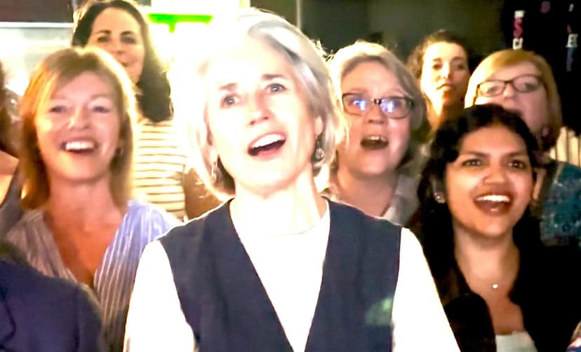 Group of people smiling and singing in a lively indoor setting