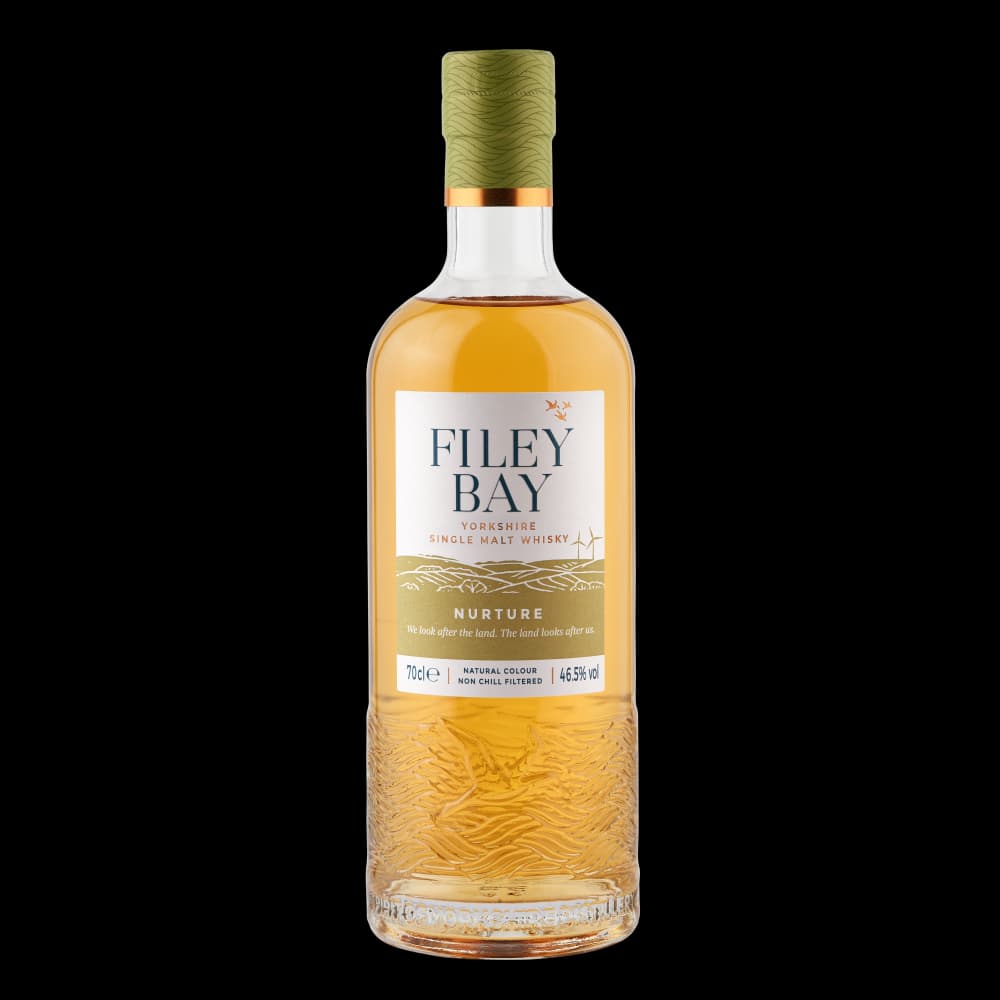 A bottle of Filey Bay Nurture single malt whisky with a golden hue, featuring a textured base and a green cork.