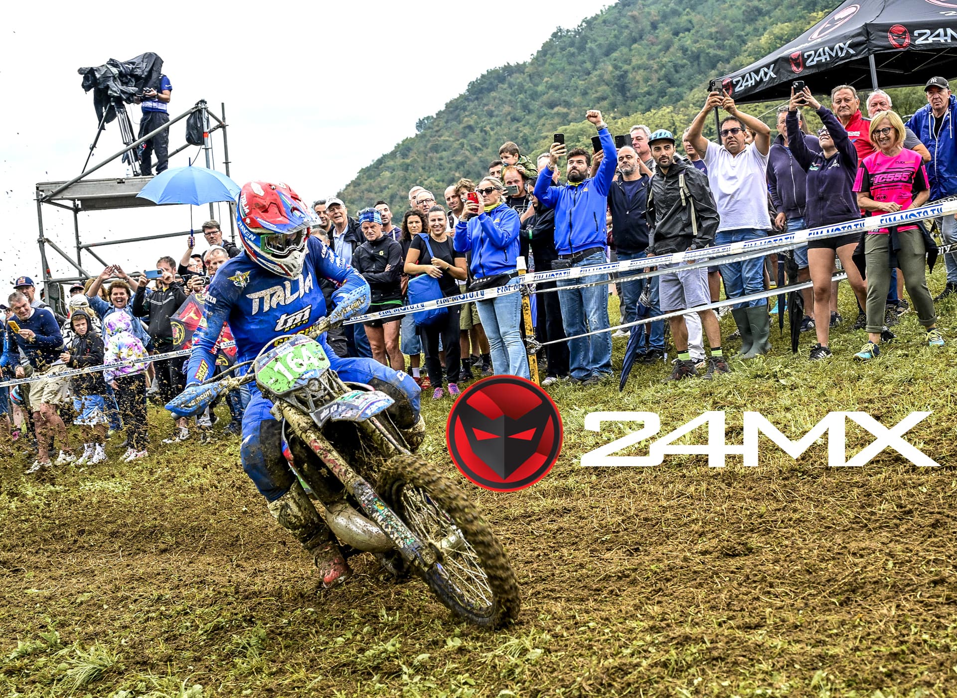 Motocross rider racing on muddy track with cheering crowd