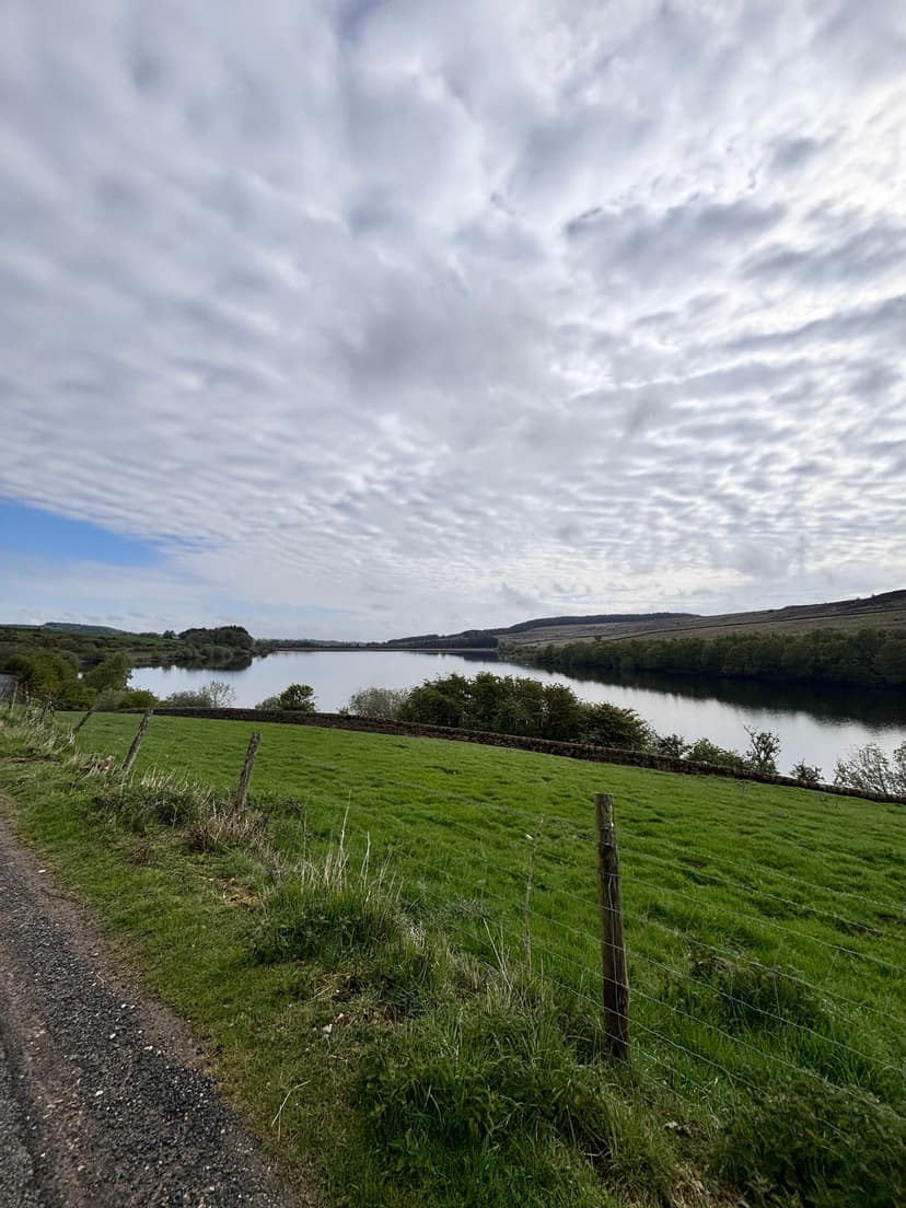 Serene lake with grassy banks under a cloudy sky in Yorkshire