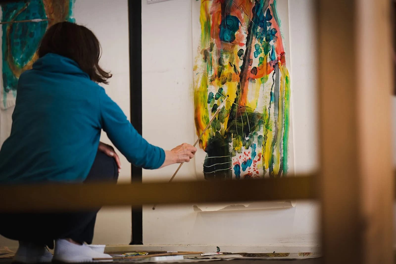 Artist in blue hoodie painting colourful abstract canvas