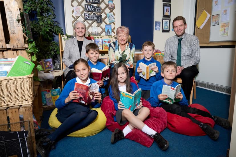 A group of children and adults in a cozy library setting, surrounded by colorful books and a warm, inviting atmosphere.