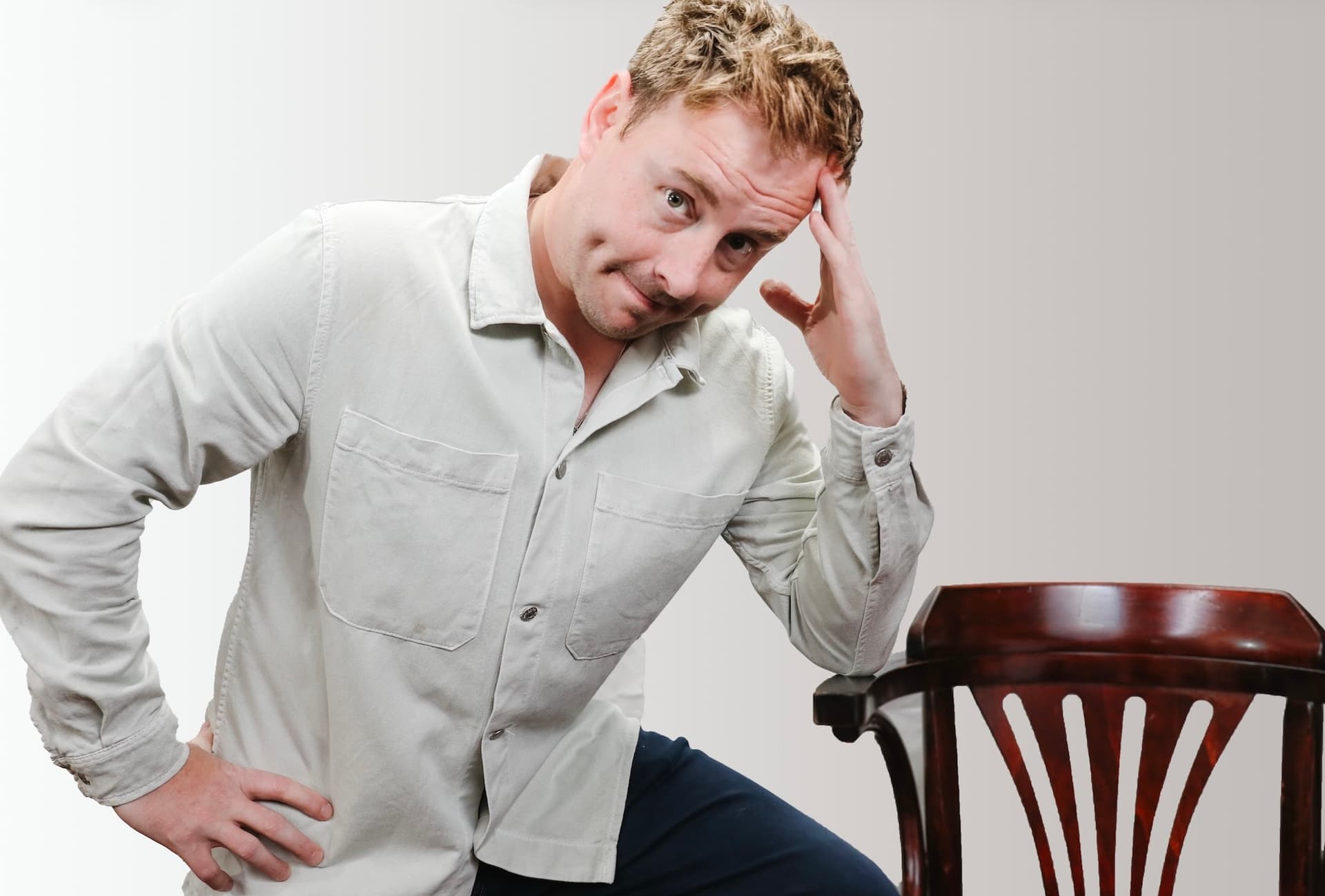 Person with a light jacket leaning on a wooden chair