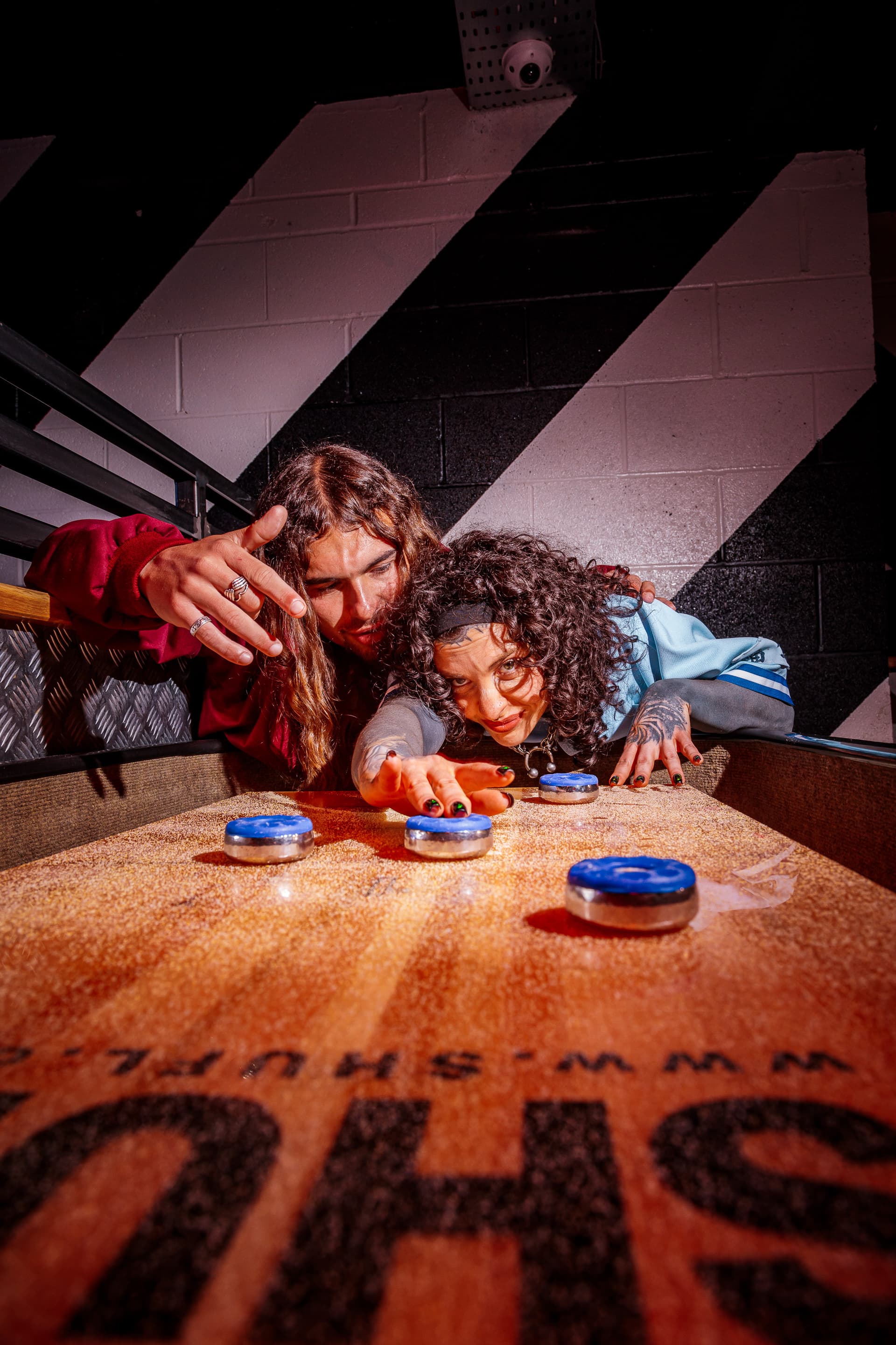 Two people playing shuffleboard in an indoor game venue