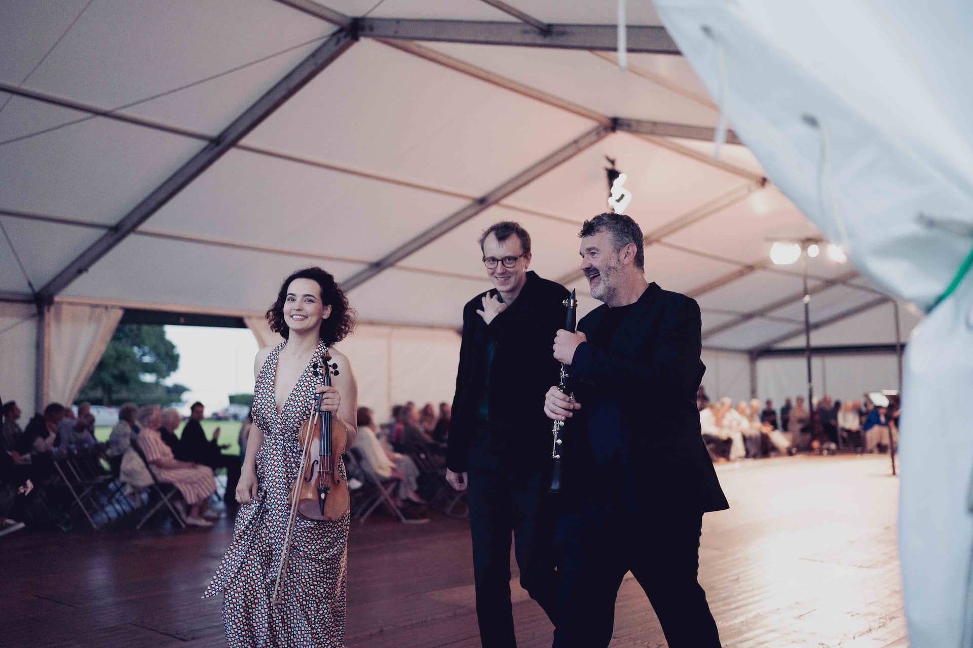 Musicians with violin and clarinet walking inside a marquee