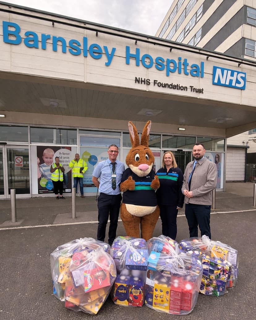 Barnsley Hospital entrance with a large Easter Bunny mascot and three Stagecoach Yorkshire colleagues beside colorful gift baskets.