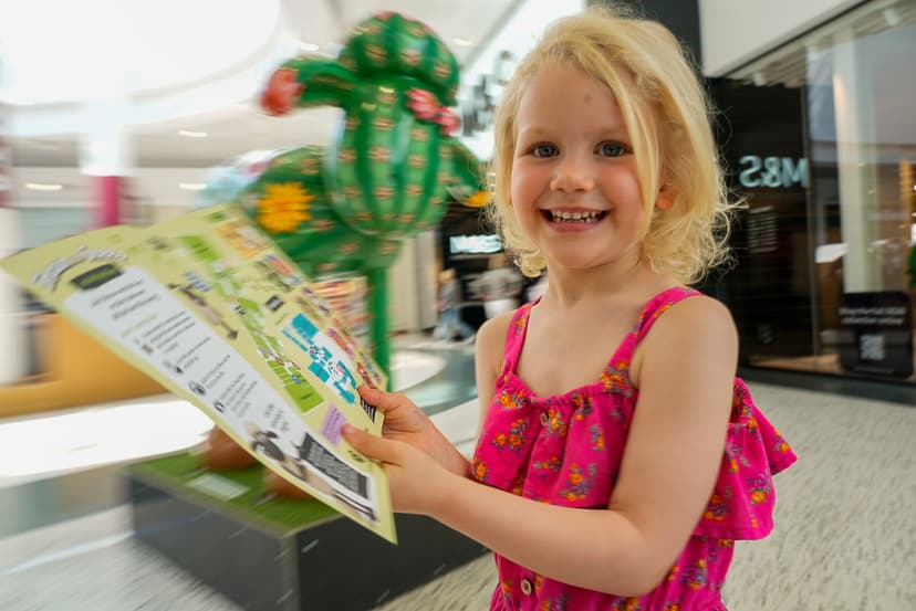 Smiling child holding a brochure in a shopping center