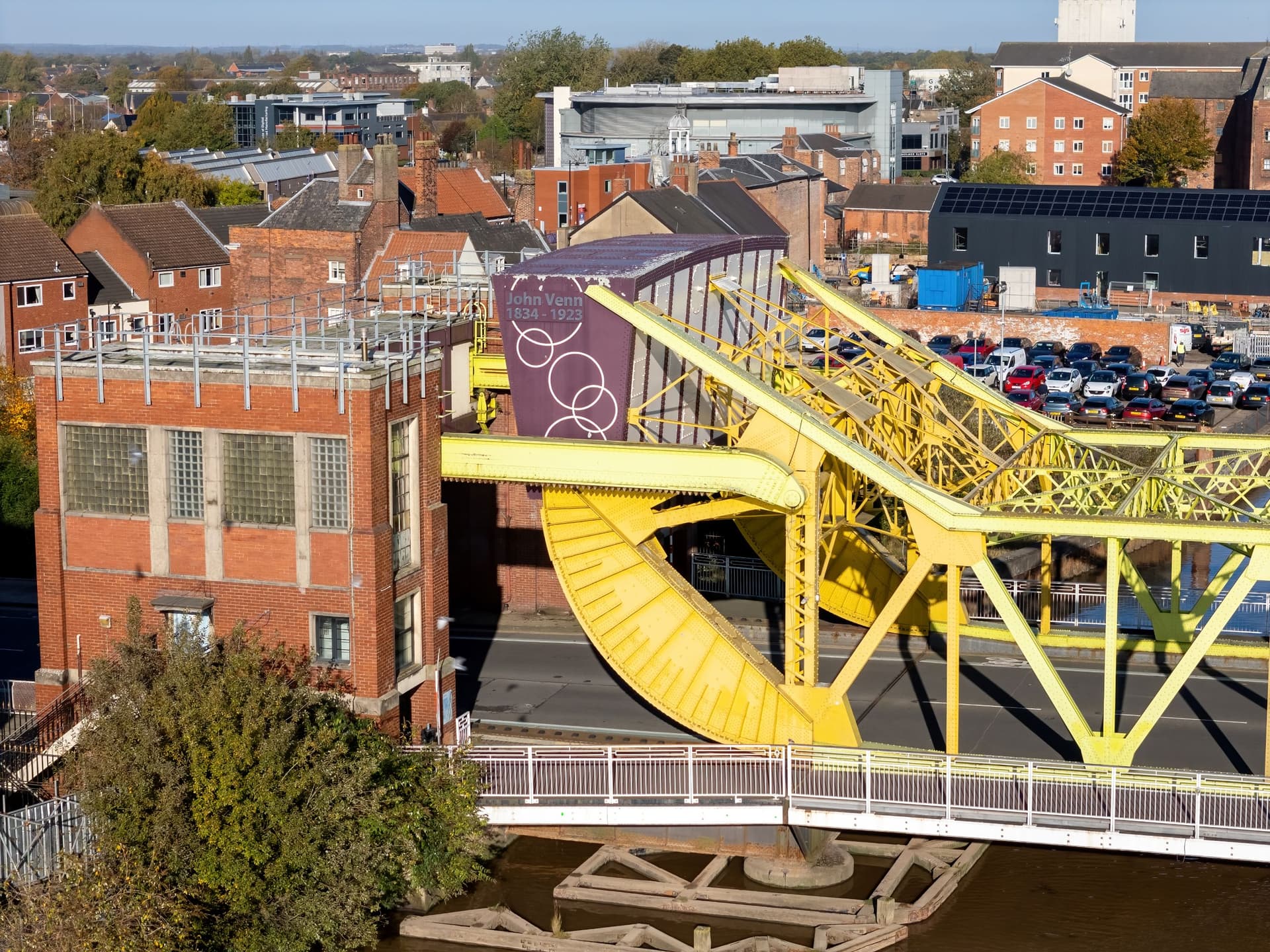 Bright yellow swing bridge over a canal in an urban setting