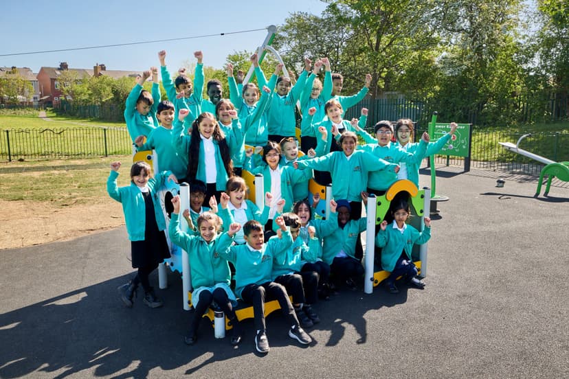 Group of schoolchildren in teal uniforms on playground equipment