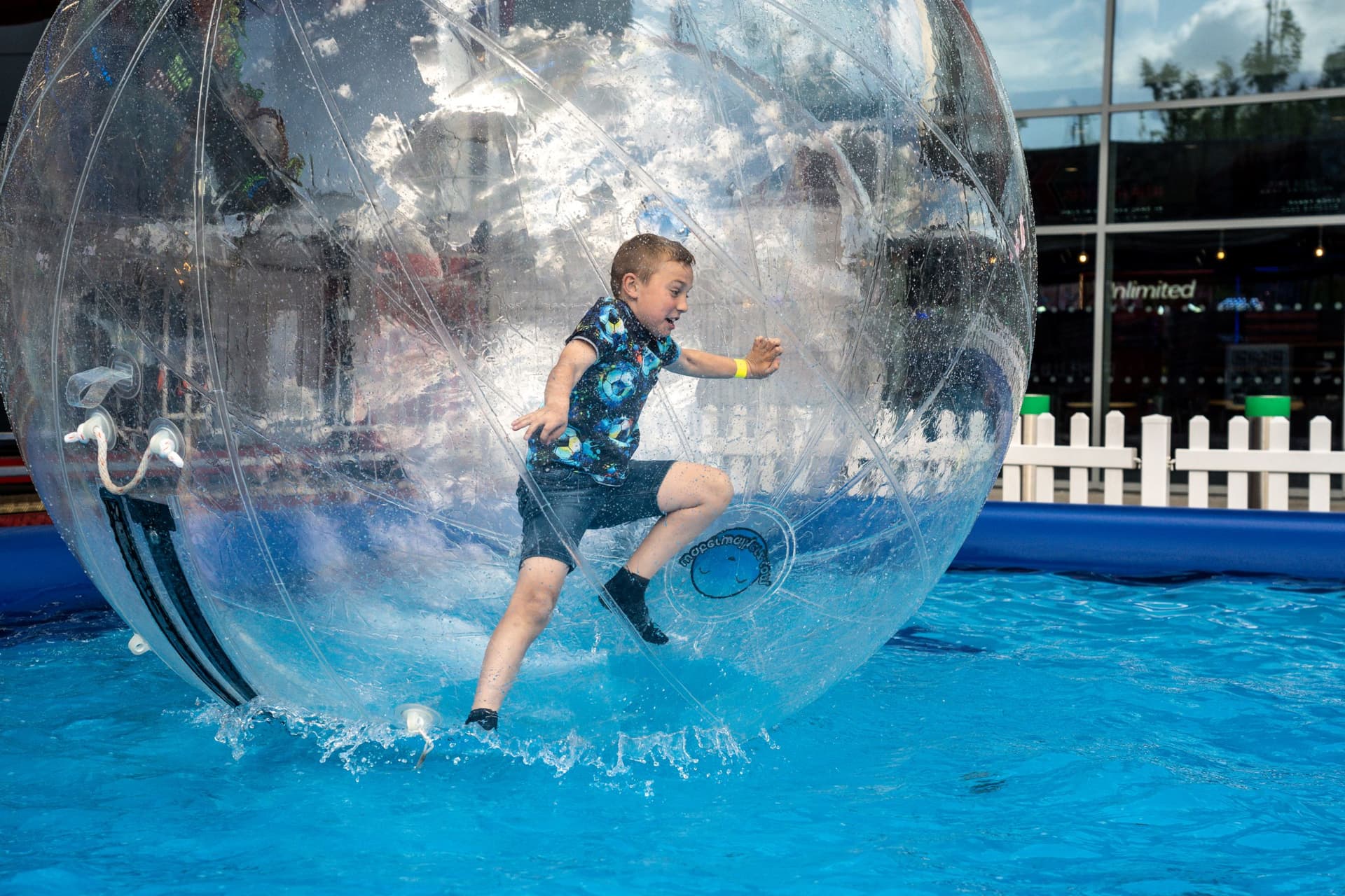Child playing inside a large inflatable water ball on a pool