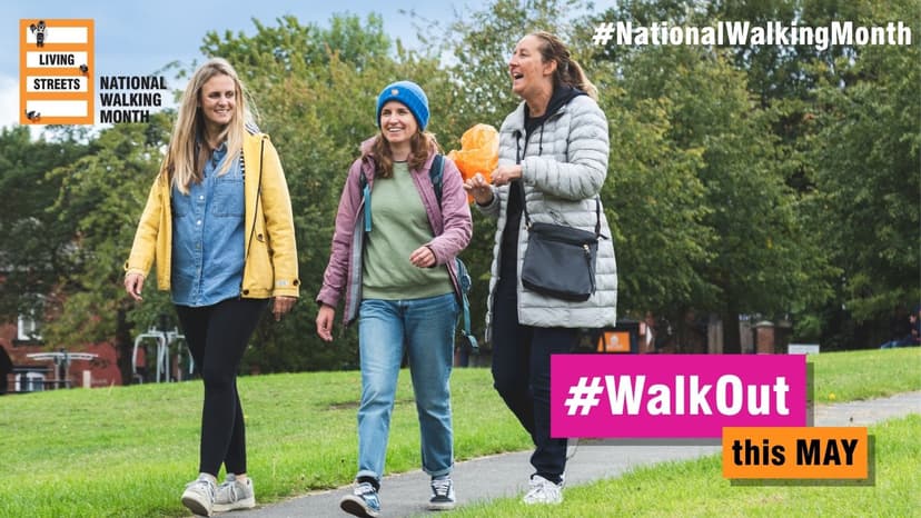 Three women walking on a park path smiling during autumn