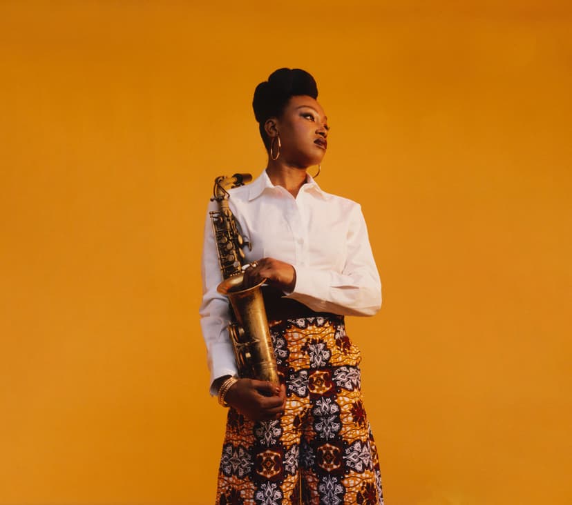 Musician holding saxophone against a warm amber background