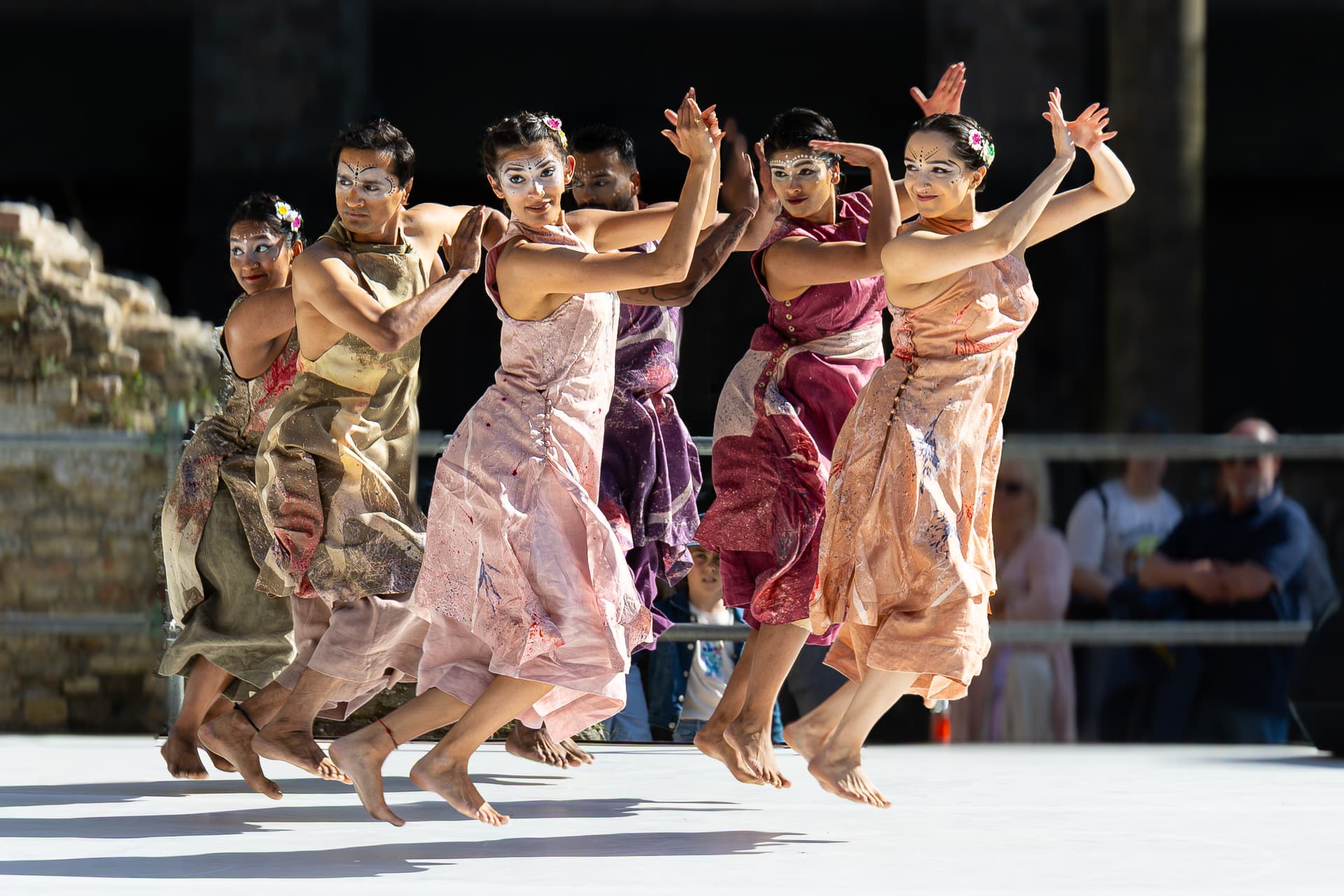 Dancers in colorful costumes performing outdoors in sunlight