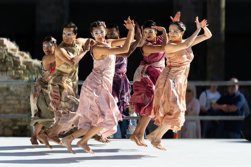Dancers in colorful costumes performing outdoors in sunlight
