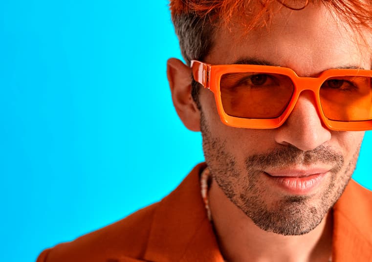 Man with orange sunglasses and blazer against blue background