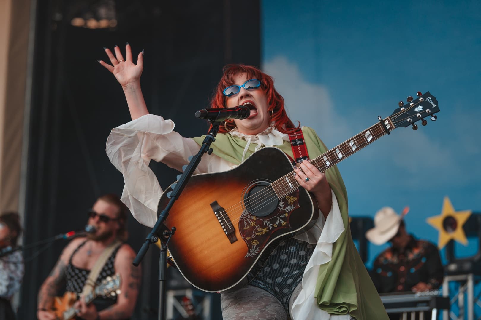 Female guitarist in colourful outfit performing on stage