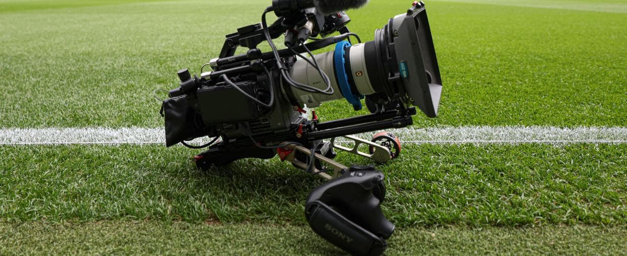 Professional video camera on lush green soccer field