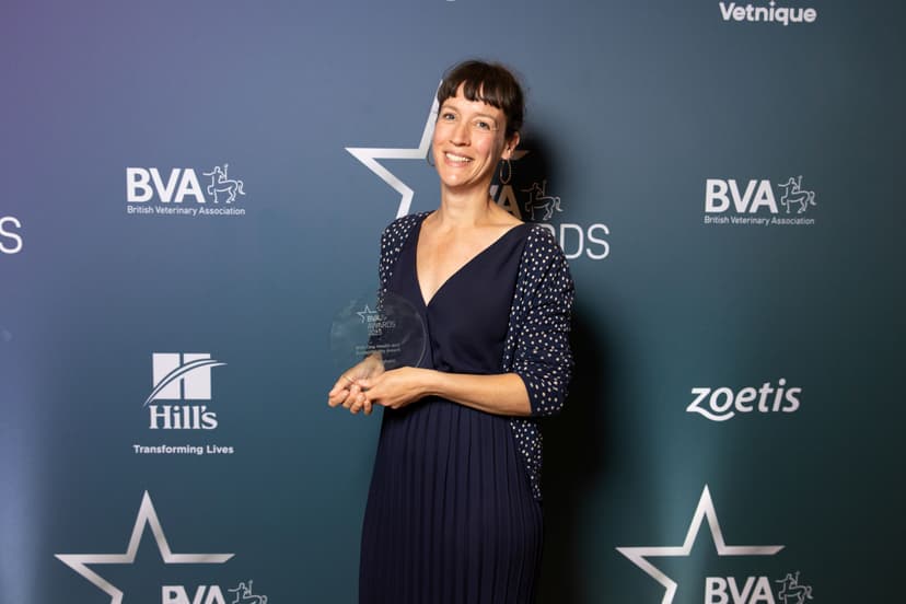 Smiling woman in a blue dress holding an award trophy